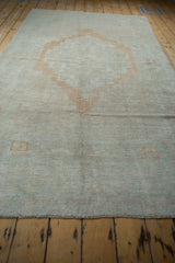 Angled perspective showing the large pale terracotta medallion on a distressed vintage Oushak carpet.