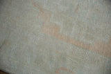 The low, hand-knotted pile of a distressed Oushak carpet showing mostly even wear.