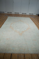 Angled view showcasing the full length and soft palette of a distressed Oushak rug.