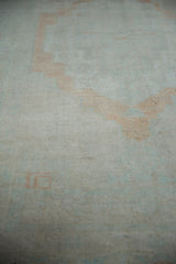 A close view of the Oushak carpet's pile, showing mostly even wear to the knot heads.