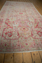 Distressed Sivas carpet pile featuring raspberry, green floral vinery, even wear, and faint foundation.