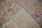Distressed Sivas rug corner folded, revealing worn raspberry and mint pile and tightly woven foundation.