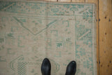 Vintage Distressed Oushak with geometric patterns in soft blue-green and antique ivory.