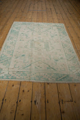 Distressed Turkish Oushak rug's end fringe with faded seafoam geometric pattern.