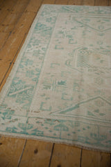 Hand-knotted Oushak rug's intact selvages, fringe, and distressed seafoam geometric pattern.
