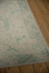 Faded distressed pile of vintage Oushak rug, showing ivory and soft seafoam patterns.