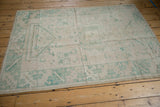 Distressed lower corner of the vintage Oushak rug, with seafoam geometric patterns and selvage.