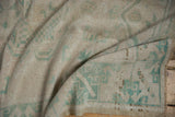 Textured pile of a vintage distressed Oushak rug, with soft seafoam blue-green geometric motifs.