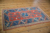 Distressed Turkish Melas rug corner, geometric cranberry, indigo, and ivory patterns.