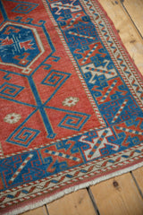 Close-up of vintage distressed Melas rug showing cranberry, indigo geometric pattern and worn pile.