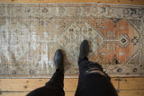 Distressed Oushak runner showing wear across knot heads, faded terracotta, blue geometric motifs.