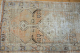 Distressed Oushak runner's geometric floral motifs, pale terracotta, and visible foundation.