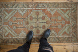 Distressed Oushak rug runner with central floral medallion in terracotta, sea foam green, and neutral tones.