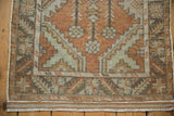 Distressed vintage Oushak runner's fringed end, with terracotta and seafoam green border.