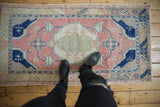 Distressed vintage Oushak runner showcasing worn texture, pink, cobalt, and sea foam motifs.