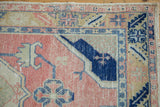 Distressed Oushak rug texture showing intricate dusty rose and cobalt blue patterns.