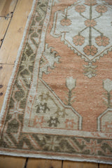Distressed Oushak runner's border featuring pale terracotta, ivory, charcoal floral-geometric patterns, even wear.