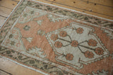 Distressed pile of a vintage Oushak runner with pale terracotta and ivory floral motifs.