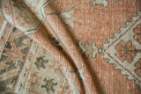 Detail of the distressed Oushak rug's pile, revealing pale terracotta and ivory patterns.