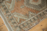 Distressed vintage Oushak rug corner showing intact side cord selvage and softened terracotta pattern.