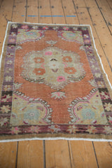 Distressed vintage Oushak rug upper corner, with purple starburst border and terracotta field.