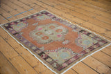 Distressed vintage Oushak rug corner, terracotta field, violet starburst floral border.