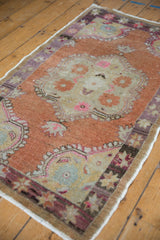 Distressed Oushak rug corner with terracotta field, playful starburst border, and blush pink details.