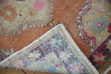 Vintage Distressed Oushak rug showing hand-knotted construction, worn pile, and terracotta, pink colors.