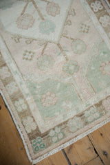 Distressed Oushak runner close-up highlighting playful sea foam, soft peach, and beige floral border patterns.