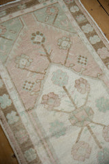 Distressed Oushak pile with pale pink, sea foam green, and beige blossoming floral motifs.