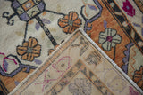 Corner view of distressed Oushak rug, showing worn orange, purple pile, fringe, and hand-knotted back.