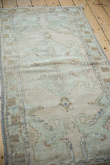 Distressed vintage Oushak runner's textured pile, with soft beige and sea foam green motifs.