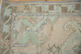 Distressed vintage Oushak runner pile, revealing beige, sea foam green, and coffee brown geometric patterns.