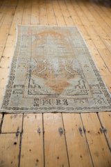 Distressed Oushak runner end, worn dusty gold and ivory pile, charcoal geometric border pattern.