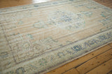 Distressed Oushak rug border, faded navy and seafoam floral patterns, visible foundation.
