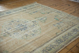 Distressed Oushak carpet pile with worn knot heads, displaying faded blue-green floral motifs.