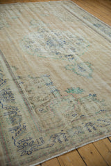 Distressed vintage Oushak carpet with worn pile, visible foundation, and faded blue and beige patterns.
