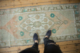 Distressed Oushak rug runner with soft floral medallion and muted designer tones.