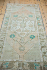 Distressed Oushak rug with faded floral patterns, featuring sand, terracotta, and dusty turquoise.