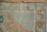 Distressed vintage Turkish Oushak rug corner with faded sand, terracotta, and turquoise floral patterns.