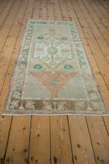 Distressed Oushak rug runner's fringed end, showing border with terracotta, sand, and turquoise motifs.