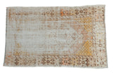 Distressed vintage Oushak rug featuring an ivory field with worn saffron and tangerine patterns.