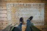 Textural view of distressed Oushak rug, showing worn areas and faded saffron yellow.