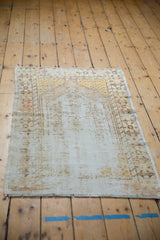 Textured distressed vintage Oushak rug corner, showing worn pile, exposed foundation, and pale saffron.