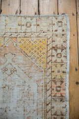 Vintage distressed Oushak rug corner highlights worn ivory, saffron pile, exposed foundation, and selvage.