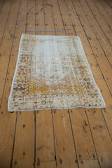Distressed vintage Oushak rug corner with saffron yellow seed motifs, pale tangerine, and visible wear.