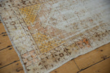 Distressed Oushak rug: worn pile, saffron yellow and tangerine floral motifs, visible foundation.