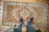 Distressed vintage Oushak rug detail with copper, silver slate, and gold floral vines and spandrels.