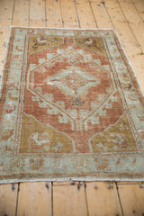 Distressed vintage Oushak rug showing worn floral vines and medallions in copper and pale slate.