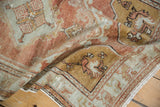 Folded vintage distressed Oushak rug showing worn copper and pale slate floral motifs.